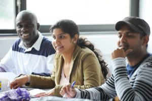 Three students in the summer program in Giessen, Germany sit at their desks and laugh.