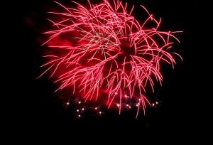 A fireworks display in the night sky showing a burst of red color.