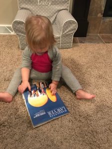 A young child sits on the floor looking at a copy of the Marquette Lawyer magazine.