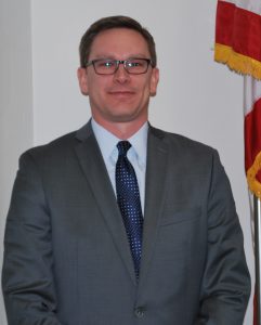 Attorney Bill Davidson stands in ront of a Wisconsin flag.