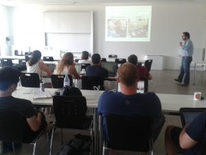 The interior of a classroom as Professor Pablo Rueda-Saiz stands at the front of the class and studdents sit attentively in their seats.