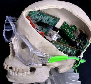 Photo of a model of a human skull with the top of the skull removed, revealing computer circuitry inside.
