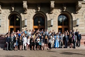 About 30 law students in semi-formal attire pose in a group photo in front of an administration building at Justus Liebig University.