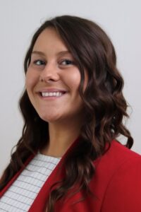 head shot of a young woman with long curly hair; her name is Dusty Gross